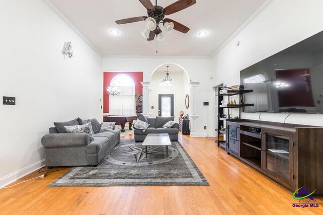 living room featuring decorative columns, hardwood / wood-style flooring, ornamental molding, and ceiling fan