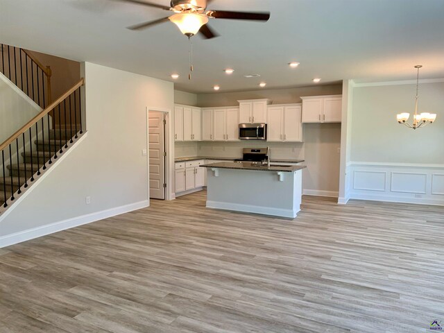 kitchen featuring stainless steel appliances, white cabinets, light hardwood / wood-style flooring, ceiling fan with notable chandelier, and a kitchen island with sink