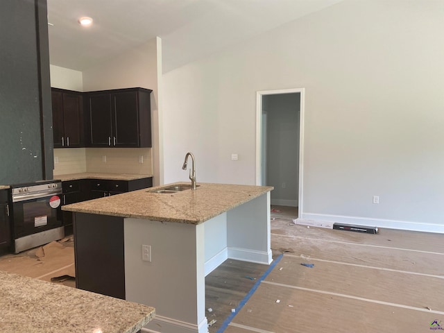 kitchen with a center island with sink, stainless steel range oven, tasteful backsplash, and sink