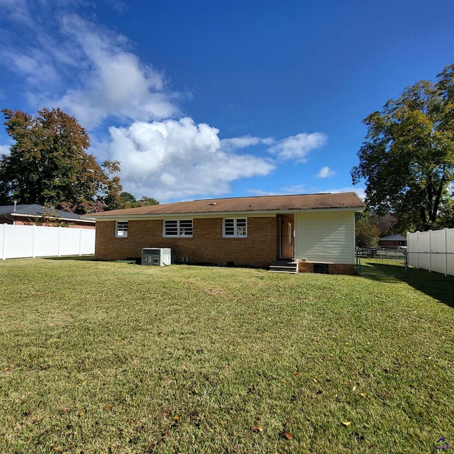 rear view of property with central AC unit and a lawn