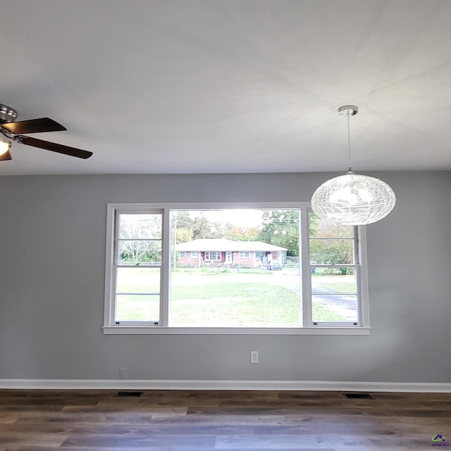 empty room with ceiling fan with notable chandelier and dark hardwood / wood-style flooring