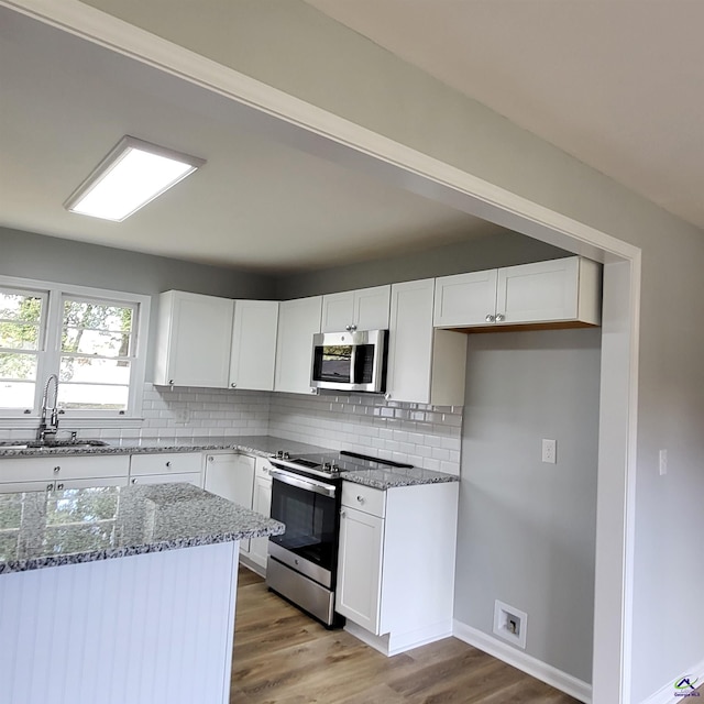 kitchen featuring white cabinets, sink, stainless steel appliances, and stone counters