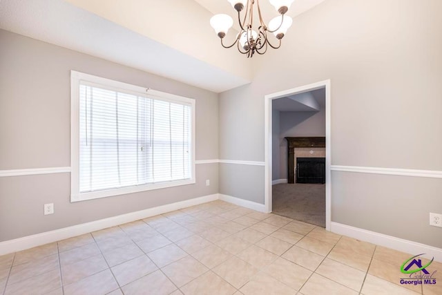 spare room featuring light tile patterned flooring, a chandelier, and lofted ceiling