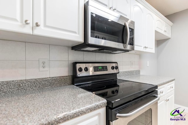 kitchen featuring decorative backsplash, white cabinets, and appliances with stainless steel finishes