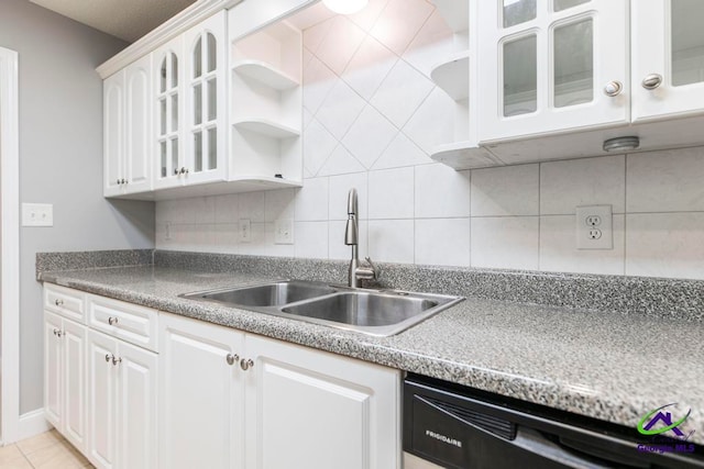 kitchen with tasteful backsplash, stainless steel dishwasher, sink, light tile patterned floors, and white cabinets