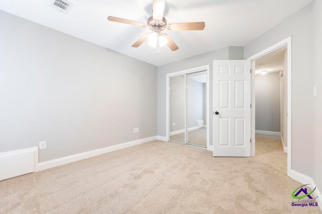 unfurnished bedroom featuring light colored carpet, a closet, and ceiling fan