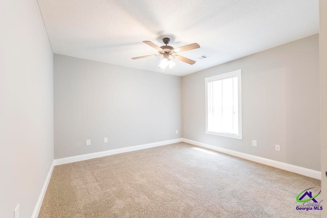 carpeted spare room featuring ceiling fan and a textured ceiling