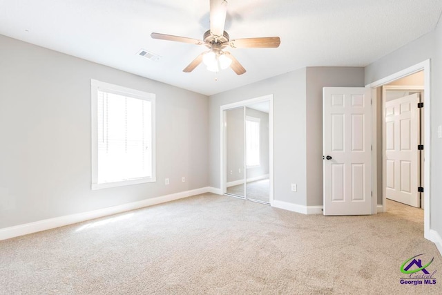 unfurnished bedroom with ceiling fan, a closet, and light carpet