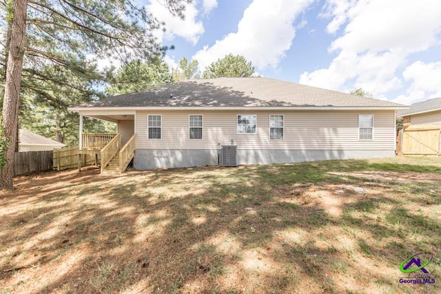 back of property with a yard and central AC