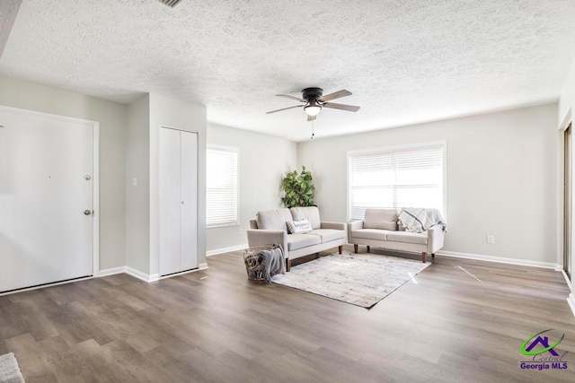 living room featuring a textured ceiling, ceiling fan, and dark hardwood / wood-style floors