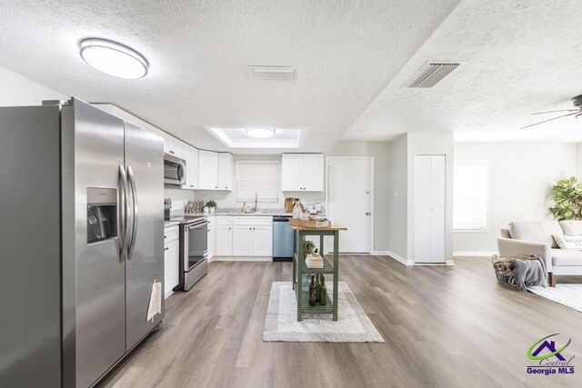 105 Westcliff Cir, Warner Robins, GA 31093 - kitchen featuring stainless steel appliances, a textured ceiling, open floor plan, wood finished floors, and white cabinets