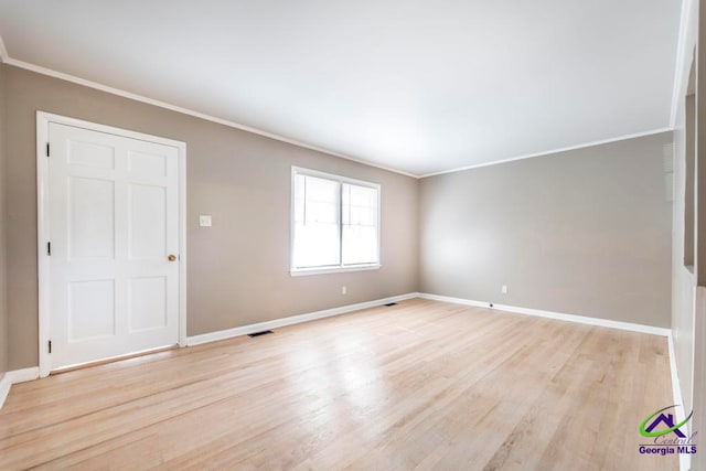 spare room featuring light wood-type flooring and crown molding