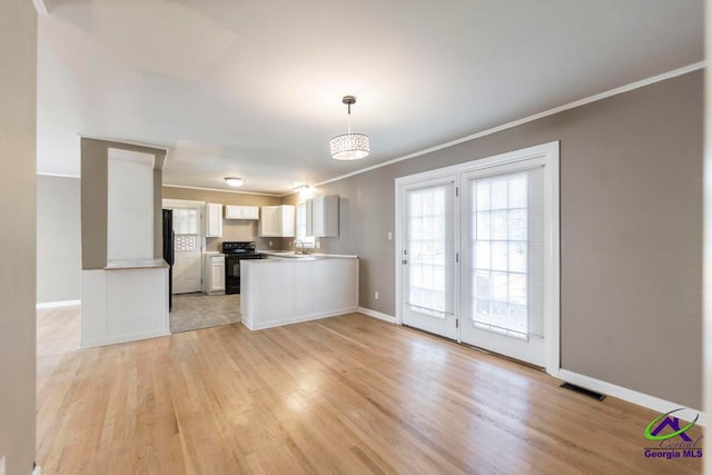 kitchen featuring white cabinets, decorative light fixtures, light hardwood / wood-style flooring, and black / electric stove