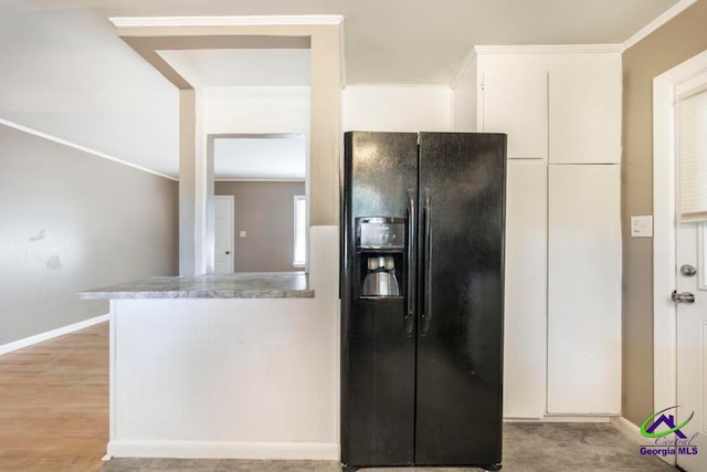 kitchen with black fridge with ice dispenser, white cabinets, light hardwood / wood-style floors, and ornamental molding