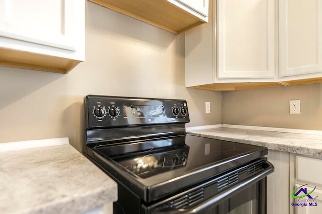 kitchen featuring white cabinetry, black range with electric stovetop, and light stone counters