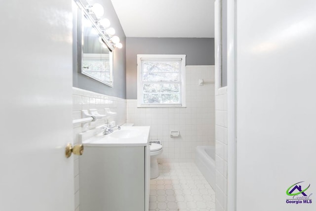 bathroom with a bathtub, vanity, tile walls, and toilet