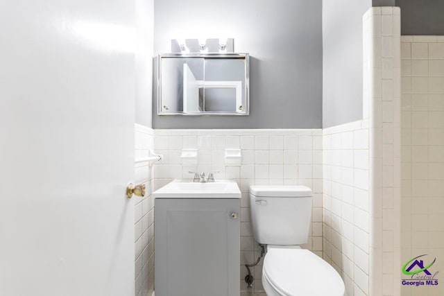 bathroom featuring vanity, tile walls, and toilet