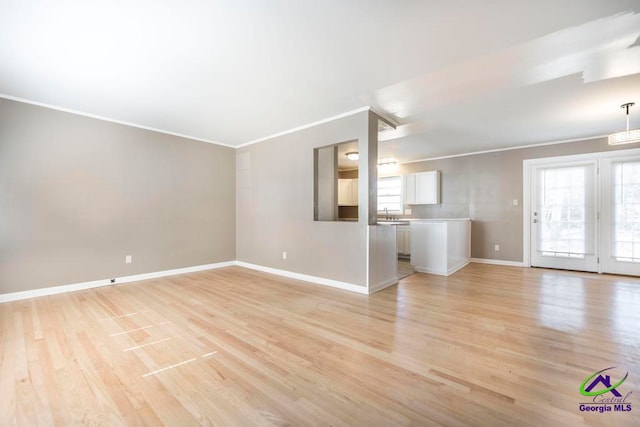 unfurnished living room featuring ornamental molding and light wood-type flooring