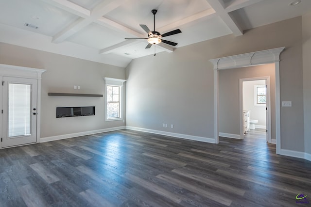 unfurnished living room featuring beam ceiling, a wealth of natural light, dark hardwood / wood-style flooring, and ceiling fan