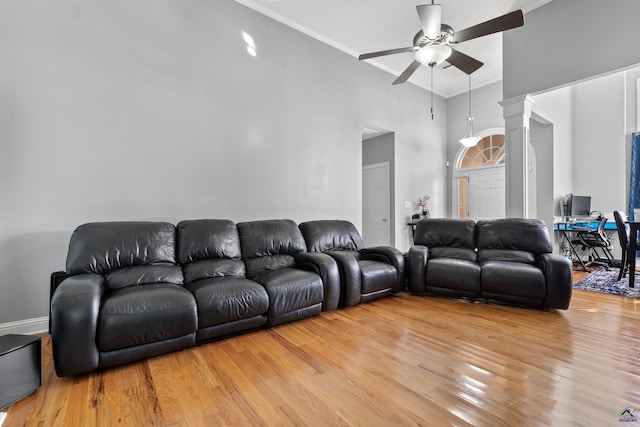 living room featuring ceiling fan, a towering ceiling, light hardwood / wood-style floors, and ornamental molding