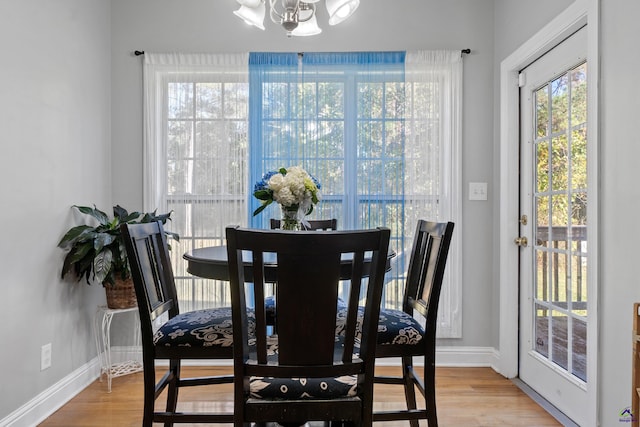 dining space with light hardwood / wood-style floors and a notable chandelier