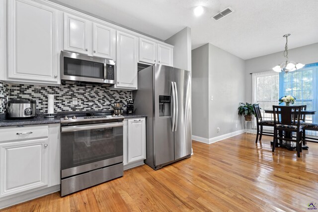 kitchen with a notable chandelier, light hardwood / wood-style floors, decorative backsplash, white cabinets, and appliances with stainless steel finishes