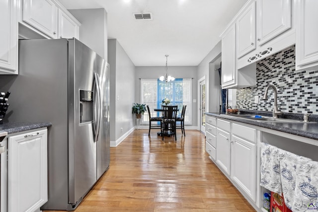 kitchen with white cabinets, light hardwood / wood-style floors, and an inviting chandelier