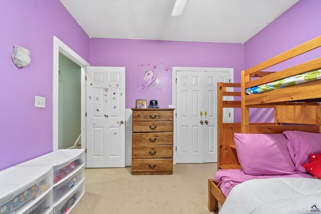 bedroom featuring light carpet, ceiling fan, and a closet