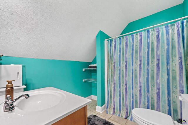 bathroom with vanity, vaulted ceiling, tile patterned flooring, toilet, and a textured ceiling