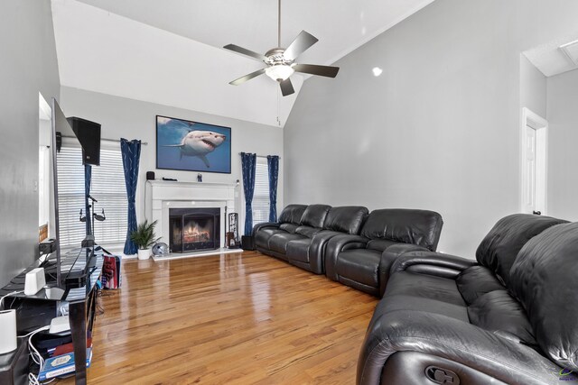 living room with hardwood / wood-style flooring, ceiling fan, and high vaulted ceiling