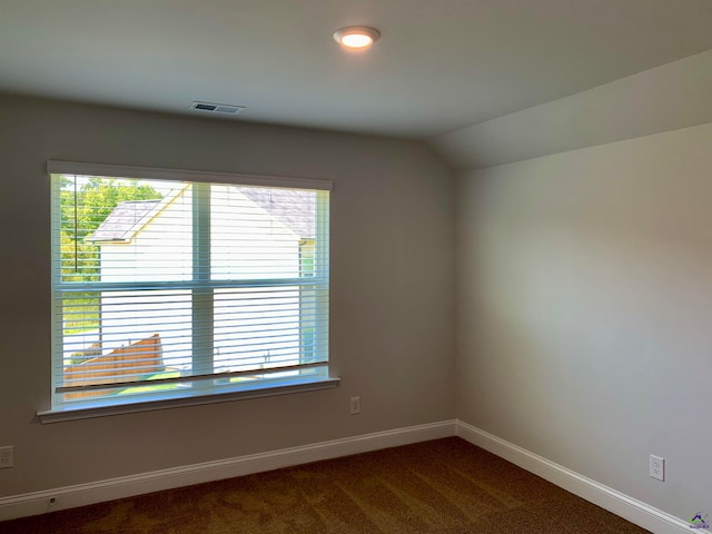 unfurnished room featuring vaulted ceiling and dark colored carpet