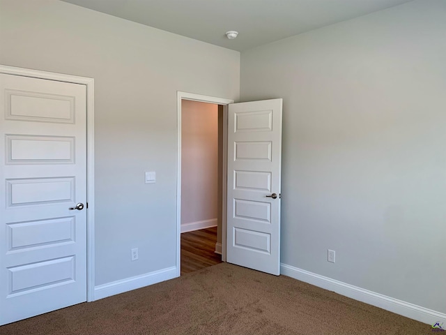 unfurnished bedroom featuring a closet and dark colored carpet