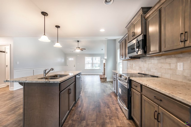 kitchen with ceiling fan, dark hardwood / wood-style floors, pendant lighting, a kitchen island with sink, and appliances with stainless steel finishes