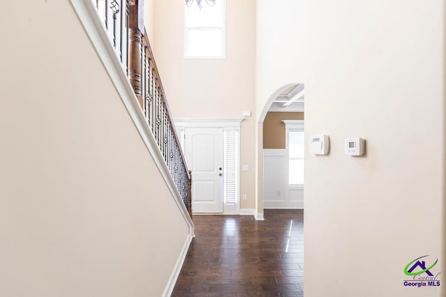 hallway with a high ceiling, dark wood-type flooring, and a healthy amount of sunlight