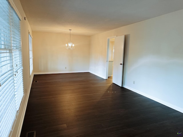 unfurnished room with dark hardwood / wood-style flooring, lofted ceiling, and an inviting chandelier