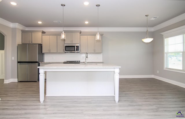 kitchen featuring gray cabinetry, a center island with sink, pendant lighting, and appliances with stainless steel finishes