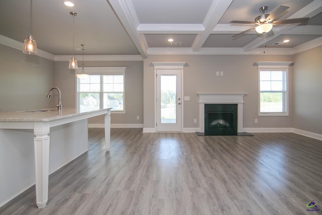 unfurnished living room featuring coffered ceiling, ceiling fan, sink, wood-type flooring, and beamed ceiling