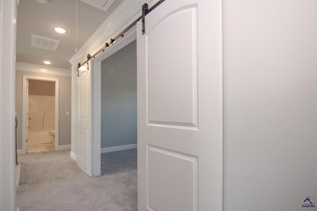 hallway featuring a barn door and light colored carpet