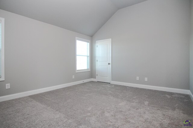 carpeted spare room featuring vaulted ceiling