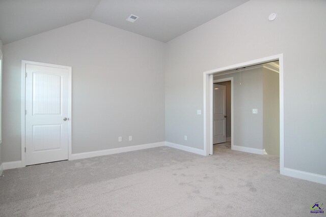 unfurnished room featuring light carpet and vaulted ceiling