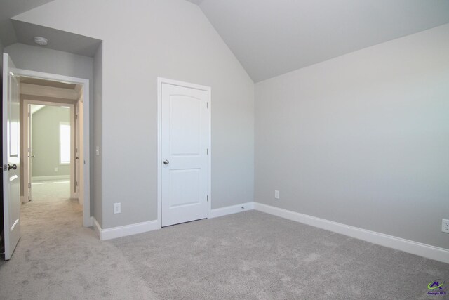 unfurnished bedroom featuring light colored carpet and vaulted ceiling