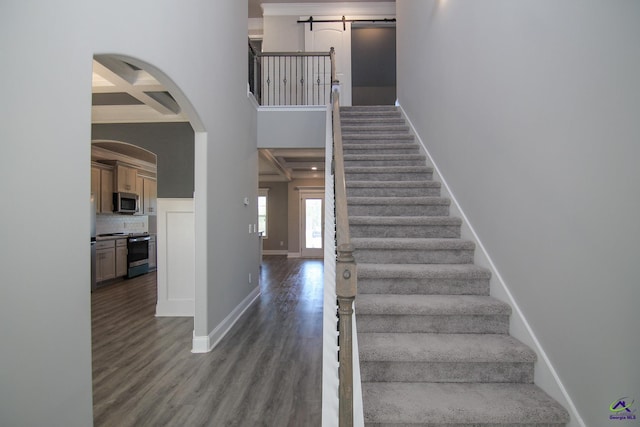 stairs with hardwood / wood-style floors, a barn door, beamed ceiling, and coffered ceiling