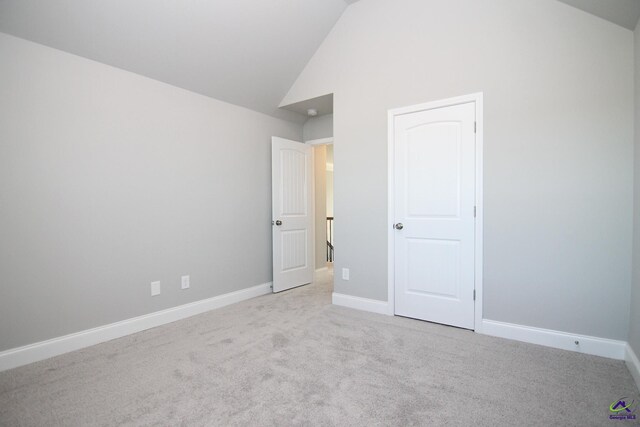 unfurnished bedroom with light colored carpet and high vaulted ceiling