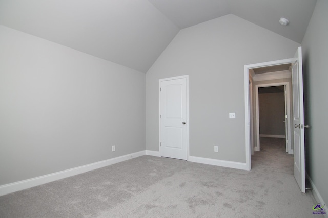 unfurnished bedroom featuring light colored carpet and lofted ceiling