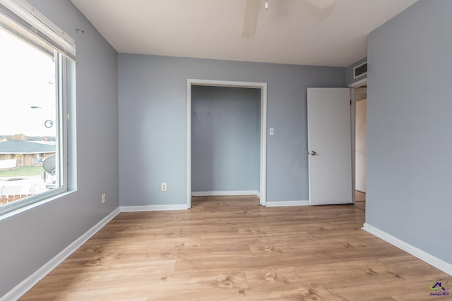 unfurnished bedroom with ceiling fan, light wood-type flooring, and a closet