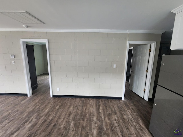 empty room featuring dark wood-type flooring, brick wall, and ornamental molding