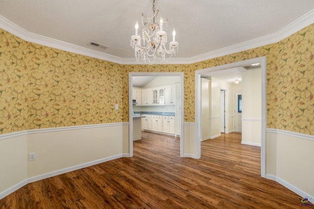 unfurnished dining area featuring a textured ceiling, hardwood / wood-style floors, a notable chandelier, and ornamental molding