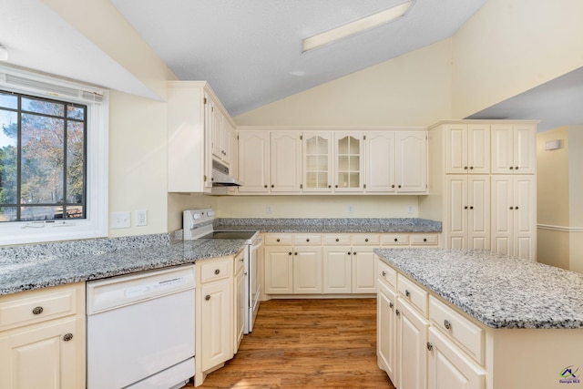 kitchen featuring light stone countertops, white appliances, light hardwood / wood-style flooring, and vaulted ceiling