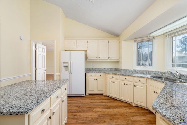 kitchen with sink, white fridge with ice dispenser, light stone counters, high vaulted ceiling, and light wood-type flooring