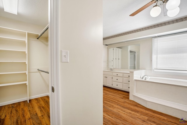 bathroom with a bathtub, vanity, hardwood / wood-style flooring, ceiling fan, and a textured ceiling